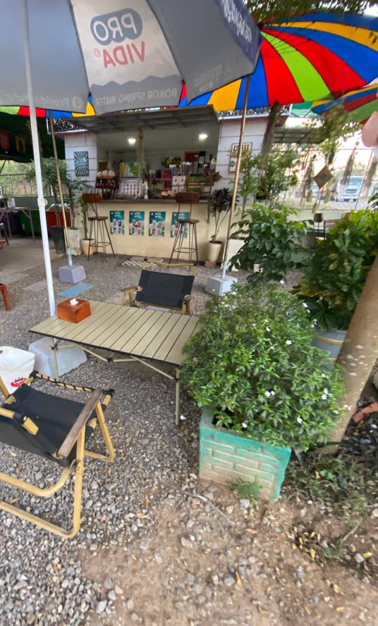 Outdoor coffee shop Cambodia with gravel floor and colorful umbrellas - The Press Day Coffee