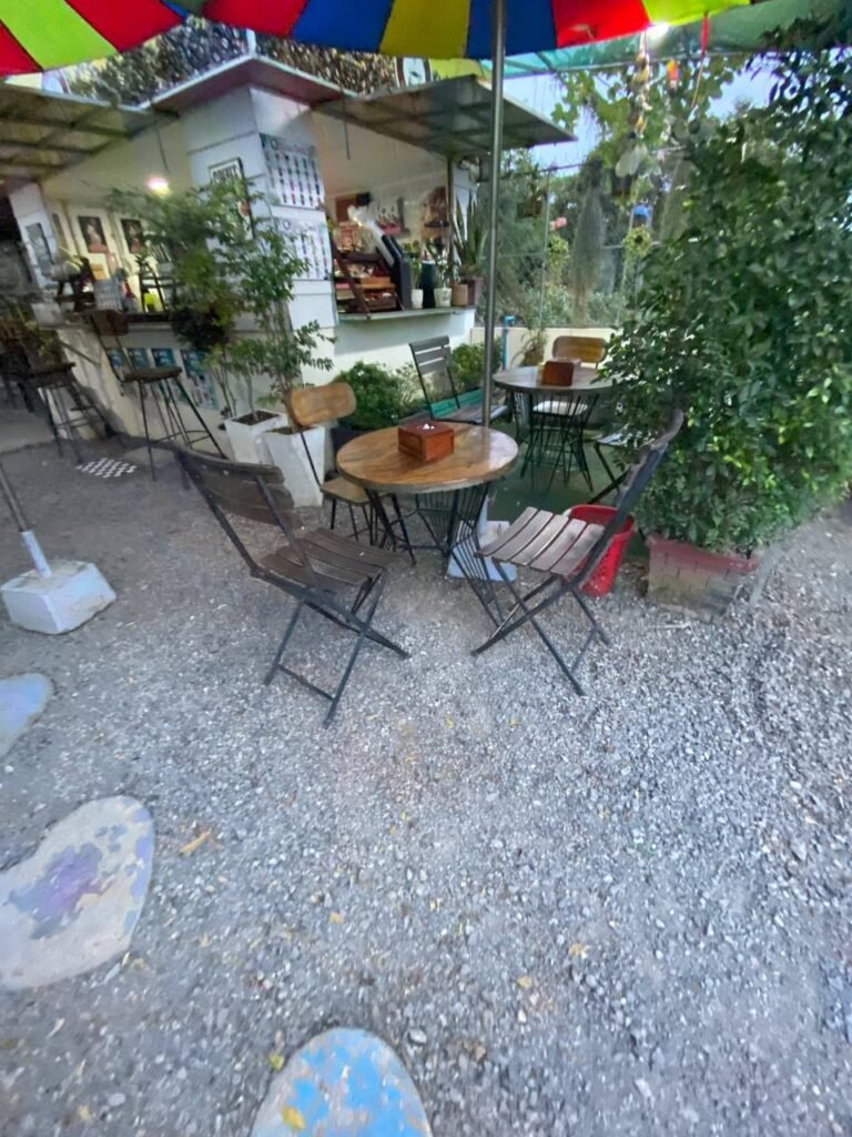 Close-up of a wooden table and folding chairs at a garden coffee shop, set up for customers.